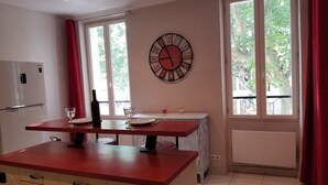 Una cucina con un piano di lavoro rosso, una sveglia al muro e una finestra con tende.