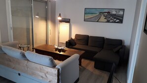 A living room with a sofa, a wooden coffee table, a lamp, and a painting on the wall. - Appartement vue mer (Veulettes Sur Mer)