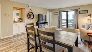 A modern living room with a dining area, a kitchen, and a balcony. - Family friendly condo, Ocean views (Tybee Island)