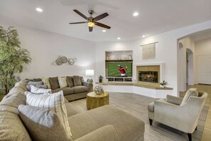 A living room with a sofa set, a coffee table, a television, a fireplace, and a ceiling fan. - Echelon: Pool, Spa, Pool Table, Ping Pong table! (Indio)