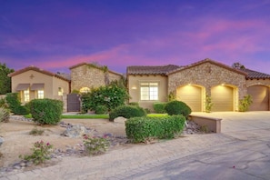 A residential property with a stone facade, multiple garage doors, and a landscaped front yard. - Echelon: Pool, Spa, Pool Table, Ping Pong table! (Indio)