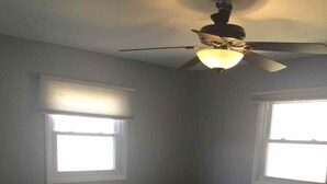 A bedroom with a bed, two windows, a ceiling fan, and a carpeted floor. - Perfect for the CrossFit Games (Fitchburg)
