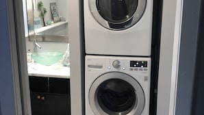 A stacked washer and dryer unit in a laundry room with a countertop and a mirror. - Perfect for the CrossFit Games (Fitchburg)