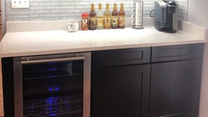A modern kitchen with dark cabinets, a stainless steel dishwasher, and a coffee maker on the counter. - Perfect for the CrossFit Games (Fitchburg)