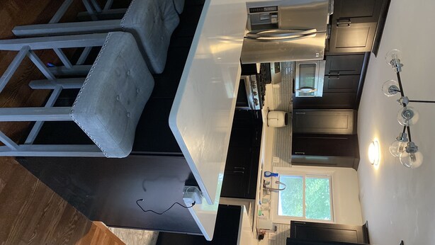 A modern kitchen with a central island, dark cabinetry, and a window providing natural light. - Perfect for the CrossFit Games (Fitchburg)