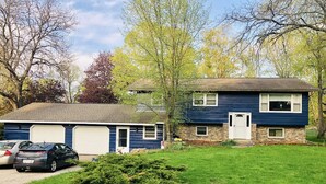 A two-story house with a garage, a small front yard, and a driveway with two cars parked. - Perfect for the CrossFit Games (Fitchburg)