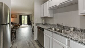 Una cocina moderna con armarios blancos, encimeras de granito y electrodomésticos de acero inoxidable.
