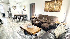 Una sala de estar con un sofá de cuero, una mesa de centro de madera y un comedor con mesa y sillas.