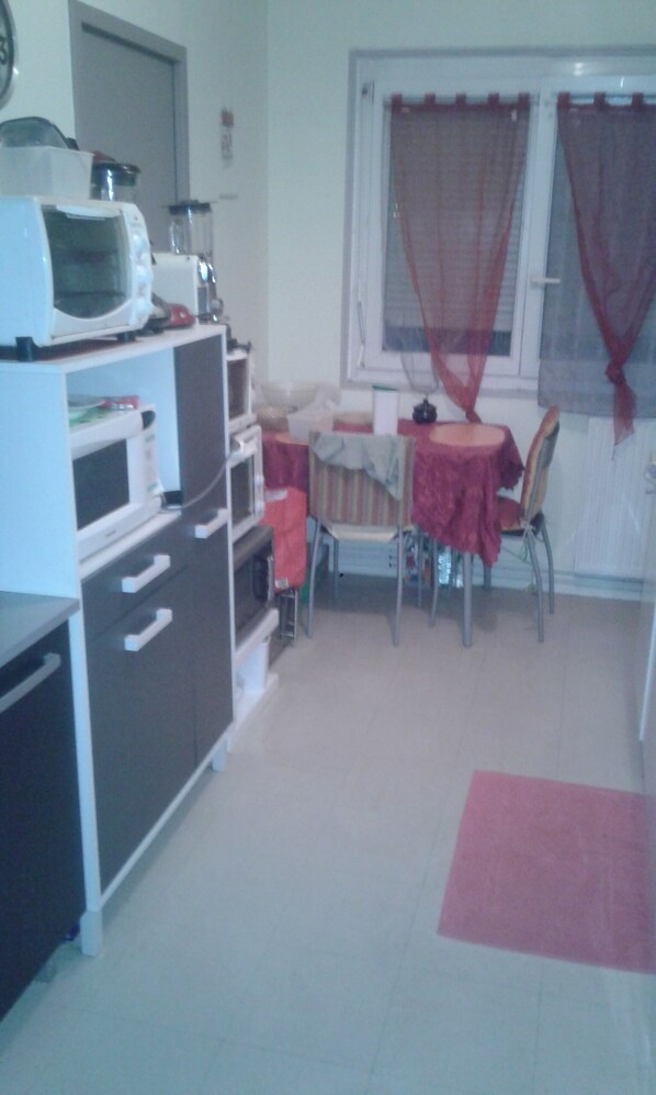 Une cuisine compacte équipée d’un four à micro-ondes, d’un four traditionnel et d’une petite table à manger avec des chaises.