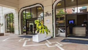 A building entrance with a large glass door, a number sign '1005', and a dinosaur statue outside. - The World Hotels (São Paulo)