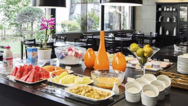 A buffet with various food items and beverages, including watermelon, apples, and orange juice. - The World Hotels (São Paulo)