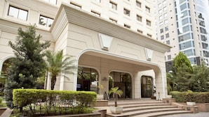 A modern hotel entrance with a grand archway, steps leading up to the doors, and well-maintained landscaping. - The World Hotels (São Paulo)