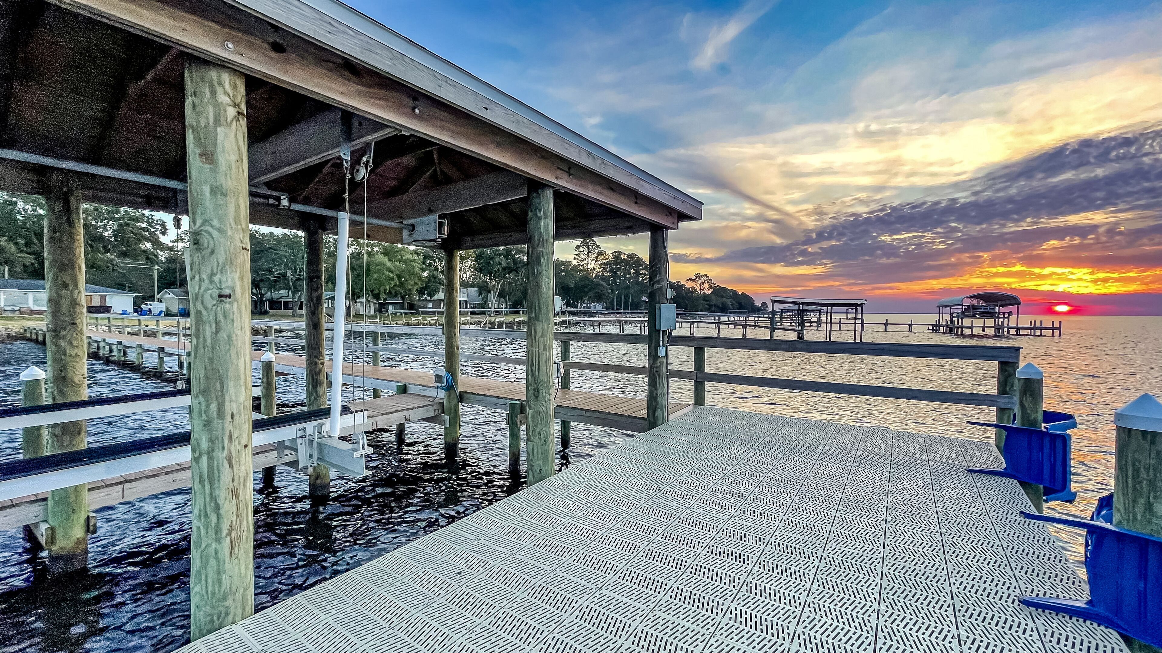 A wooden pier extending over water with a sunset in the background.