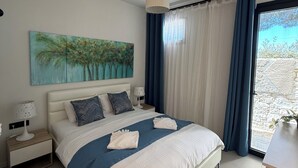 Een hotelkamer met een groot bed, een nachtkastje, een lamp, een schilderij en uitzicht op het omliggende landschap.