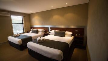 A hotel room with two beds, each with a pillow and a rolled towel.