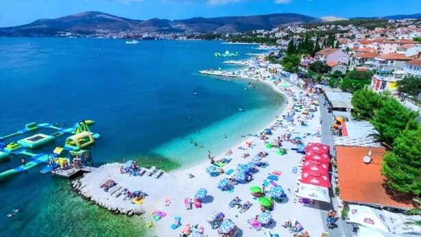 Un pueblo costero con playa, barcos y un muelle.