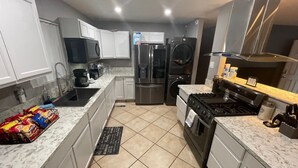A modern kitchen with white cabinets, a stainless steel refrigerator, a microwave, a stove, and a sink. - SECURE FAMILY HOME/ VACATION/ WORK SPACE ECT. (NORTH LAS VEGAS, NV)