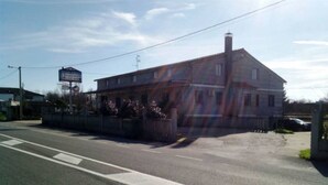 A two-story building with a signboard, a parking lot, and a road.