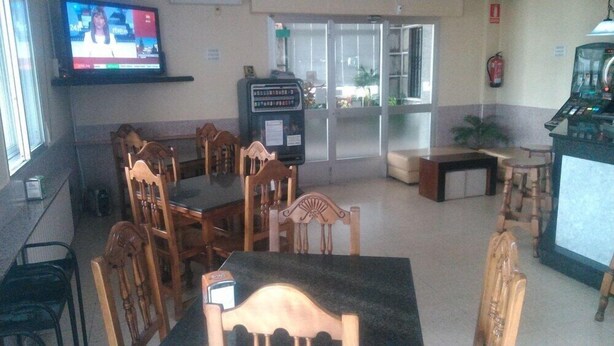 A dining area with wooden chairs and tables, a television mounted on the wall, and a fire extinguisher on the wall.