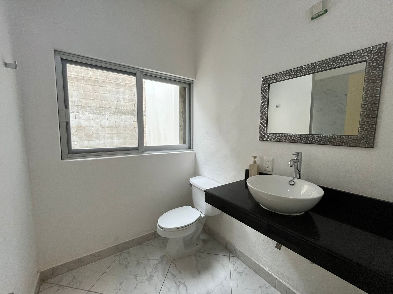 Ein Badezimmer mit Toilette, Waschbecken, Spiegel und Fenster.