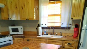Une cuisine avec des meubles de rangement en bois, un îlot central, un four à micro-ondes, un évier et un réfrigérateur.