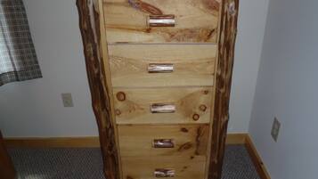A wooden dresser with five drawers and a top shelf, featuring a natural wood finish and metal handles.