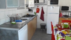 Una cocina compacta equipada con lavavajillas, estufa, microondas y un pequeño cubo de basura.