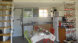 Una cocina con mesa, sillas, una escalera y un televisor.
