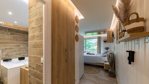 Een moderne slaapkamer met een houten kast, een bed met uitzicht en een badkamer met douche en wastafel.