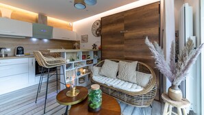 Een moderne woonkamer met een bank, rieten stoelen, een bijzettafeltje en een decoratieve vaas.