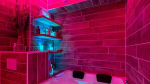 Een wellnessruimte met een houten wand, een massagetafel en een plank met decoratieve objecten.