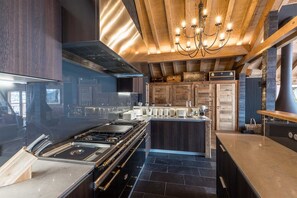 Una cocina moderna con una isla central, electrodomésticos de acero inoxidable y techo de madera.