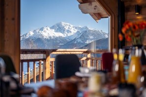 A wooden interior with a view of snow-capped mountains.