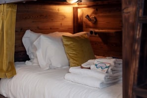 Bed dressed with soft pillows and towels, a yellow curtain adding a pop of colour - Chalet Époustouflant au Calme avec Vue Imprenable! (Les Allues)