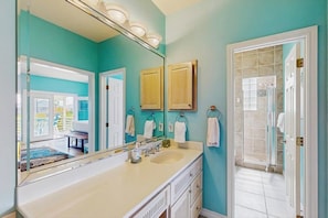 A bathroom with a large mirror, a sink, and a shower area.