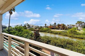 A balcony with a view of a river, palm trees, and houses.