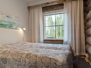 Une chambre à coucher avec un lit, une fenêtre avec des rideaux, un tableau au mur et une lampe.