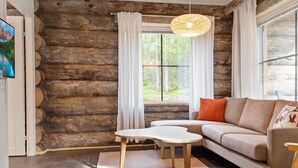 A log cabin interior with a sofa, a small table, and a hanging light fixture.