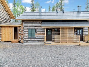 Eine Blockhütte mit Kiesweg, Holzterrasse und Metalldach.