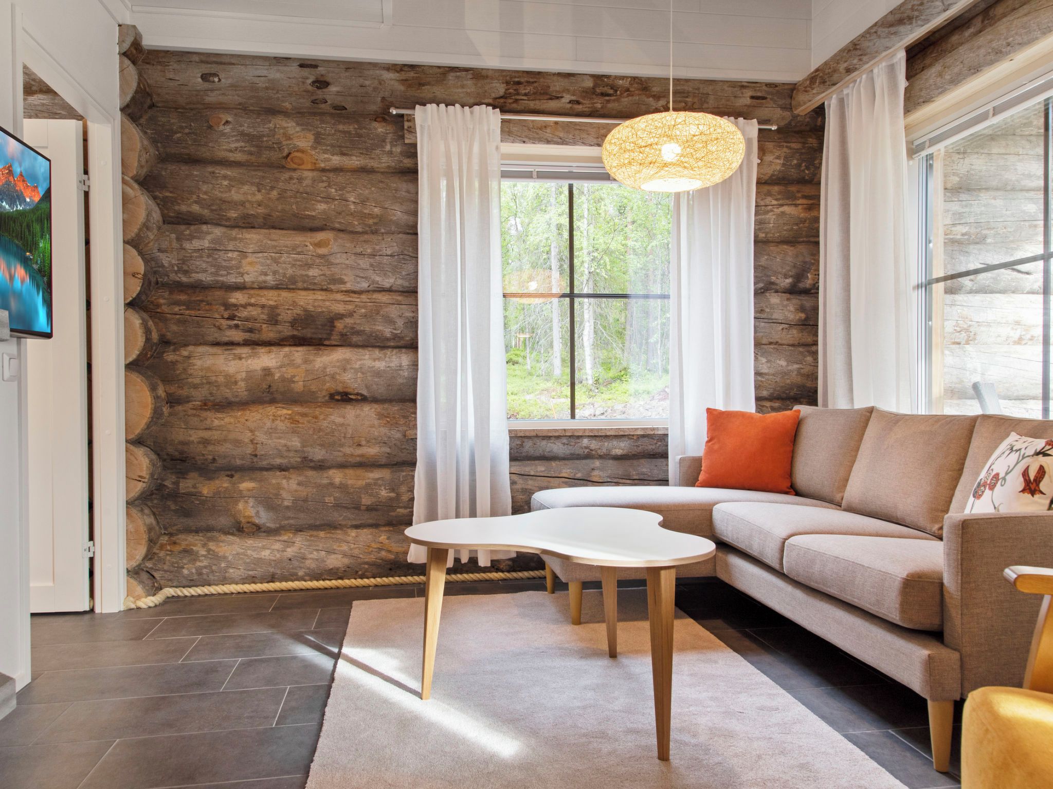 Ein Blockhaus-Interieur mit einer Couch, einem Tisch und einer Hängelampe.