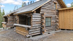 A log cabin with a sloped roof, a front porch, and a chimney.