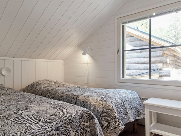 Un dormitorio con dos camas, una ventana y una pared blanca.
