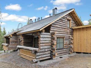 Een vakantiehuisje van hout met een veranda, schoorsteen en raam.