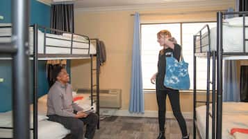 Un dormitorio con literas, una ventana con cortinas y un radiador.