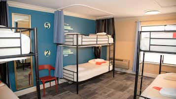 A dormitory room with bunk beds, a mirror, a chair, and a number on the wall.