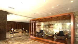 Un hall con mostrador de recepción, zona de estar y pared de piedra.