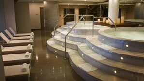 Un área de spa con un jacuzzi, zona de estar y escalones que llevan al mismo.