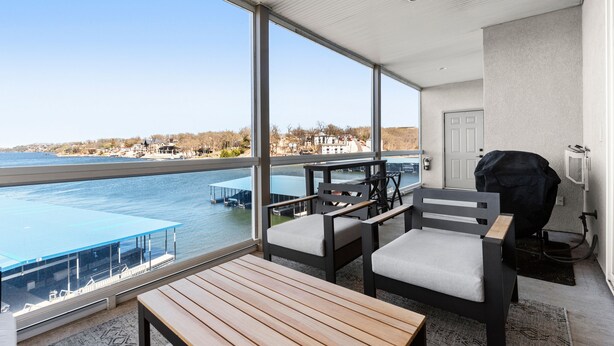 Een balkon met uitzicht op een wateroppervlak, een barbecue en een zithoek.