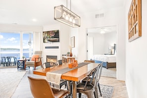 A spacious dining area with a wooden table, chairs, and a modern chandelier.