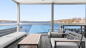 Een overdekt terras met uitzicht op een waterpartij en verre gebouwen.